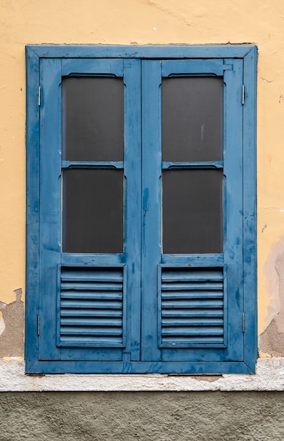 Finestra blu della casa coloniale brasiliana in un muro giallo