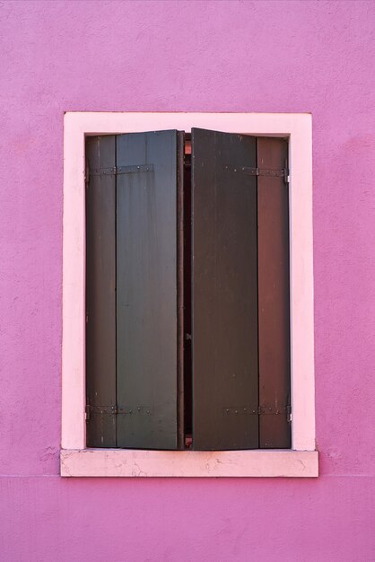 Finestra con otturatore verde sulla parete rosa. Italia, Venicw, isola di Burano.