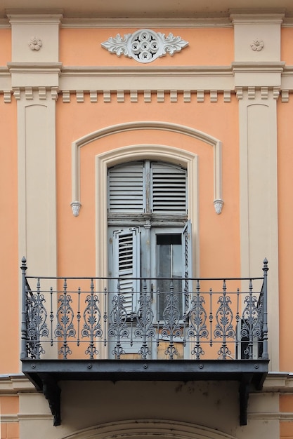 Finestra e balcone con recinzione in ferro vecchio stile sulla parete arancione con ornamenti