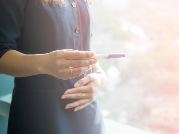 Finestra facente una pausa della ragazza nell&#39;alba di mattina con un test di gravidanza