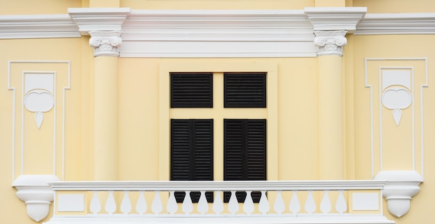 Finestra in legno classico presso l&#39;edificio in cemento arancione pallido