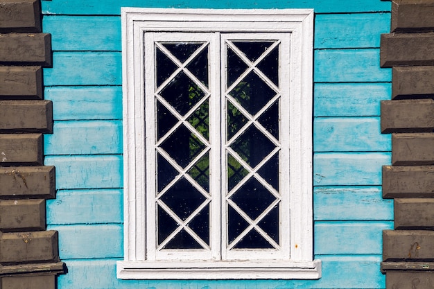 Finestra nella vecchia casa di legno blu in estate