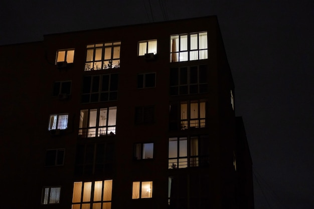 Finestre illuminate di notte edificio di appartamenti a più piani Finestre notturne illuminate di casa Sfondo della vita cittadina