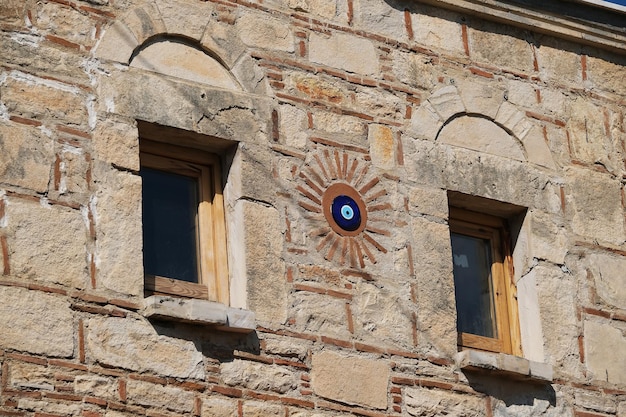 Finestre sul muro di pietra della casa con l'ornamento dell'amuleto Nazar sulla facciata