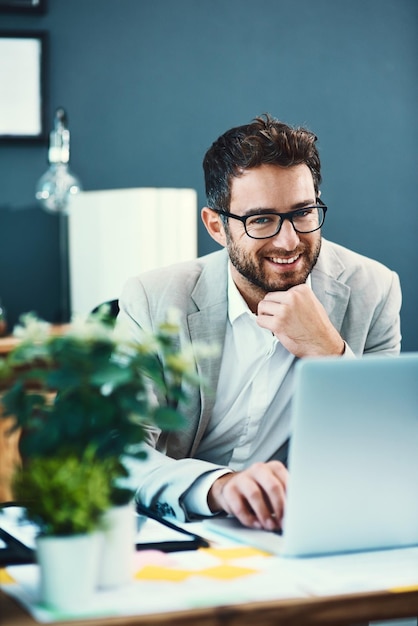 Finora è stata una giornata di successo Ritratto di un giovane uomo d'affari che lavora su un laptop in un ufficio