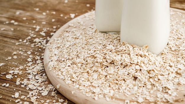 Fiocchi d'avena e bottiglia di latte fresco su una tavola di legno. Fondo rustico in legno