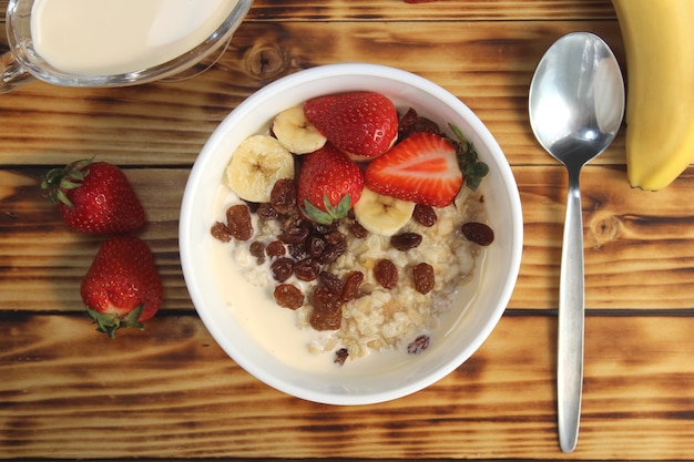 Fiocchi di avena con frutta condita con yogurt su un tavolo di legno cibo sano corretto per la colazione un piatto pieno di deliziosa polenta