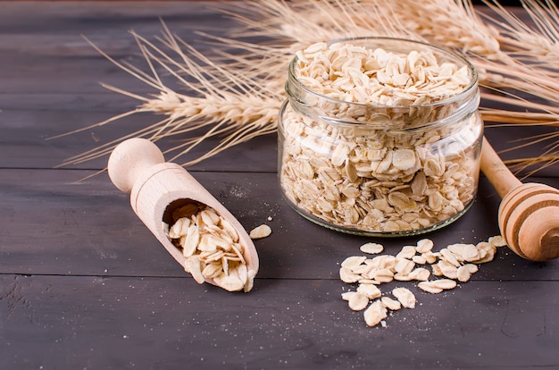 Fiocchi di avena in barattolo di vetro e cucchiaio di legno e spighette