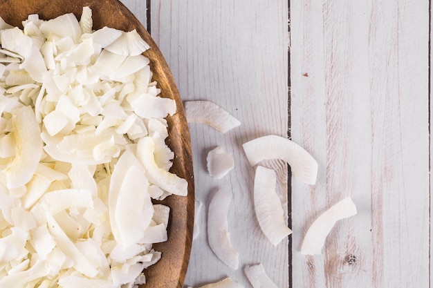 Fiocchi di cocco disidratati in ciotola di legno.