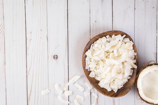 Fiocchi di cocco disidratati in ciotola di legno.