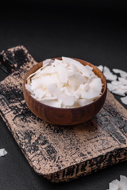 Fiocchi di cocco secchi bianchi in una ciotola di legno preparata per fare dolci