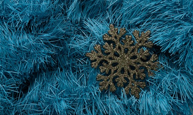 Fiocco di neve artificiale su uno sfondo blu tinsel decorazione albero di natale decorazione carta da parati vista dall'alto