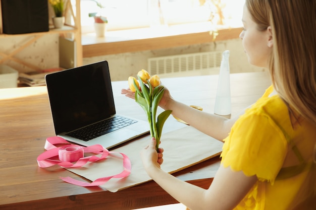 Fioraio al lavoro: la donna mostra come realizzare un bouquet con i tulipani.