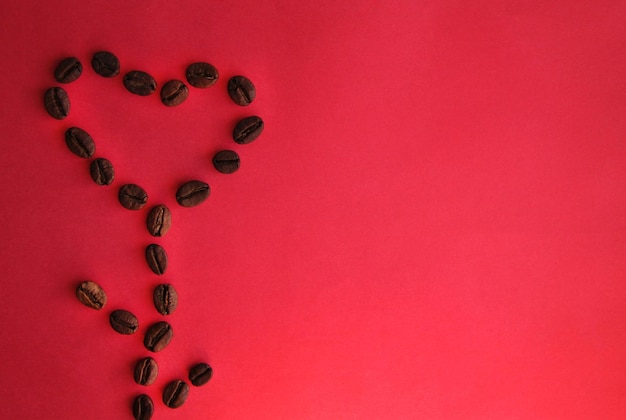 Fiore a forma di cuore di chicchi di caffè su sfondo rosa