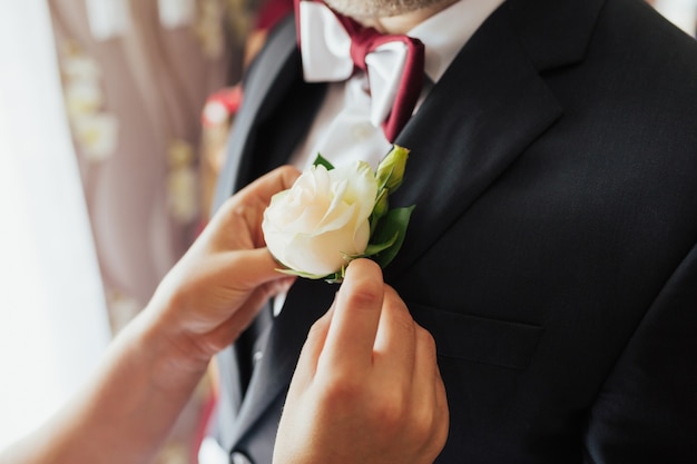 Fiore all'occhiello di rosa bianca sulla giacca da sposa dello sposo