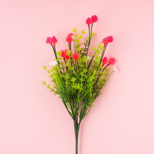 Fiore artificiale su sfondo rosa chiaro.