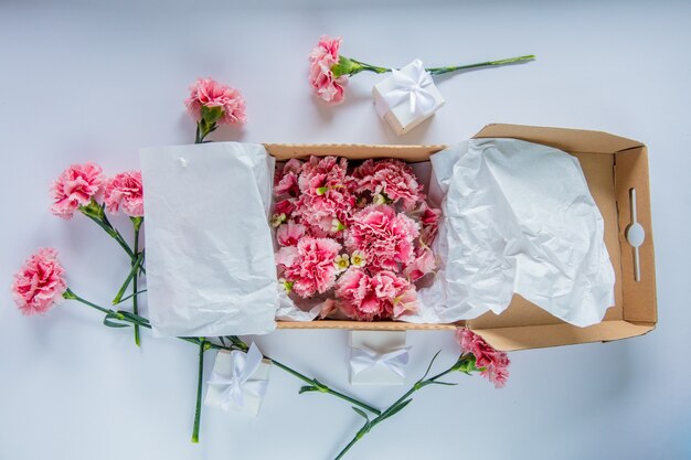 Fiore di dianthus fresco in una confezione regalo sul tavolo bianco. Concetto di ora legale