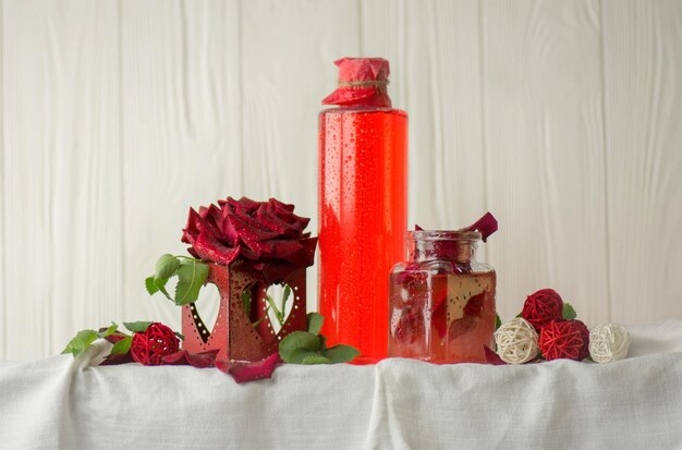 Fiore di rosa rosa e bicchiere di acqua di rose Acqua di rose organica fresca Acqua di rose in bottiglia di vetro