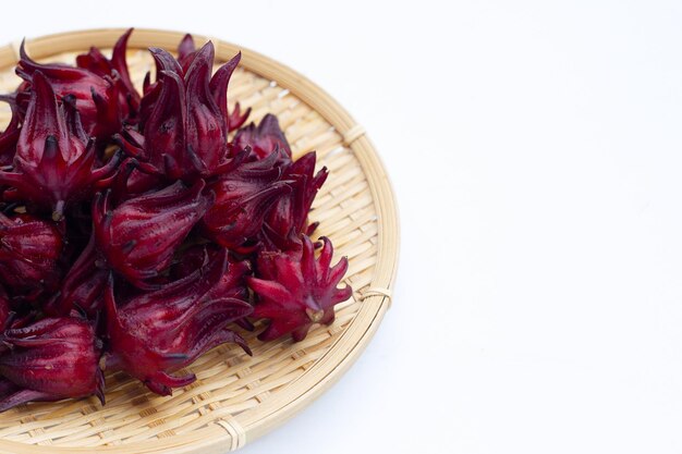 Fiore di Roselle in cesto di bambù rotondo su sfondo bianco.