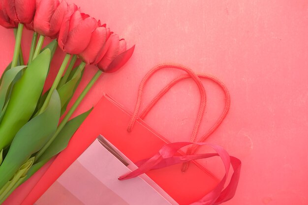 Fiore di tulipano di colore rosso in una borsa della spesa su sfondo rosso con spazio di copia