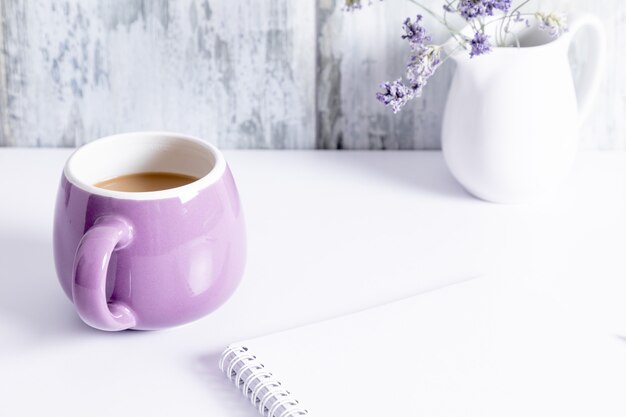 Fiore e taccuino della tazza di caffè sulla tavola grigia di legno