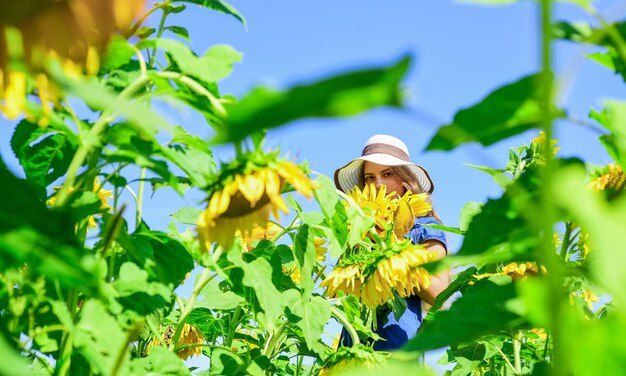 Fiore giallo di girasole infanzia felice bella ragazza indossare cappello estivo di paglia nel campo bel bambino con fiore bellezza della natura estiva bambina nel campo di girasoli cresciuto con amore