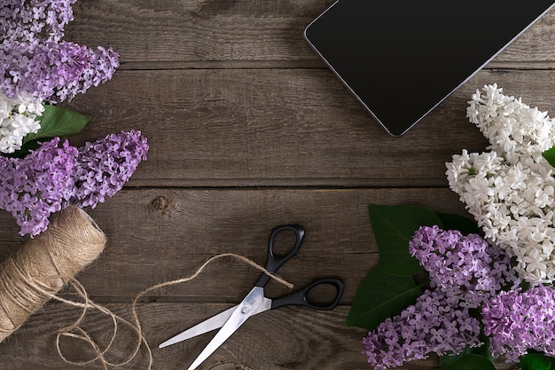 Fiore lilla su fondo di legno rustico con spazio vuoto per il messaggio di saluto tablet forbici tre...