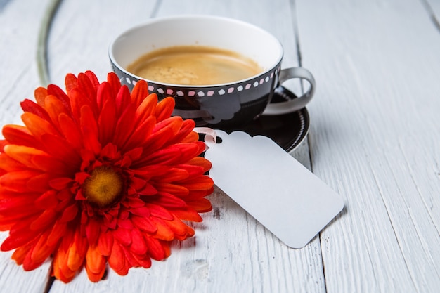 Fiore rosso, tazza di caffè sul tavolo bianco con carta pulita