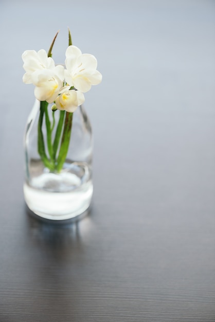 Fiori bianchi freschi in vaso di vetro sul tavolo, con lo spazio della copia.