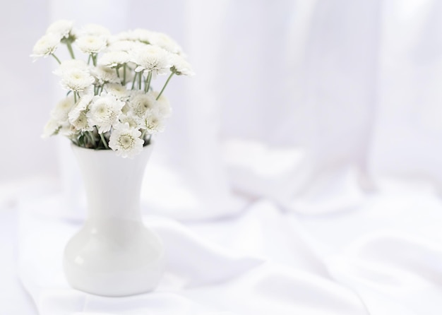 Fiori bianchi in vaso bianco su sfondo bianco con spazio per la copia e messa a fuoco selettiva Biglietto di auguri o invito