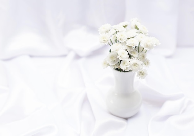 Fiori bianchi in vaso bianco su sfondo bianco con spazio per la copia e messa a fuoco selettiva Biglietto di auguri o invito