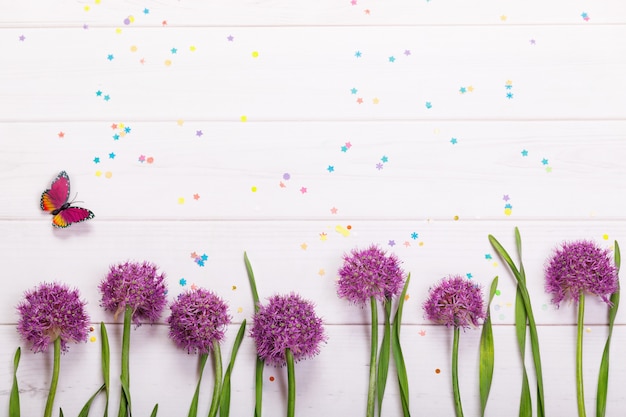 Fiori, coriandoli e farfalla della cipolla su fondo di legno. Ciao concetto di primavera.