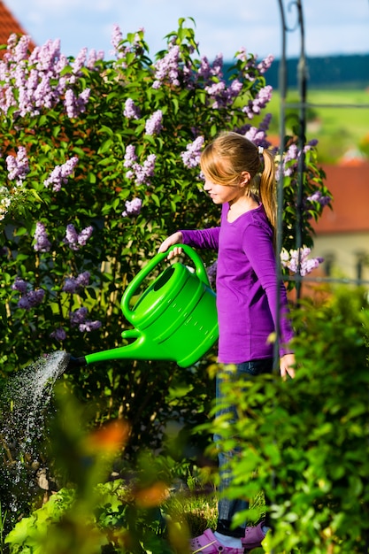 Fiori d'innaffiatura del bambino felice nel giardino