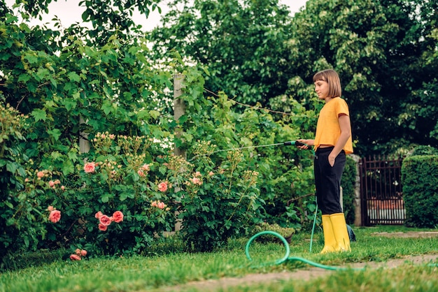 Fiori d'innaffiatura della ragazza nel giardino