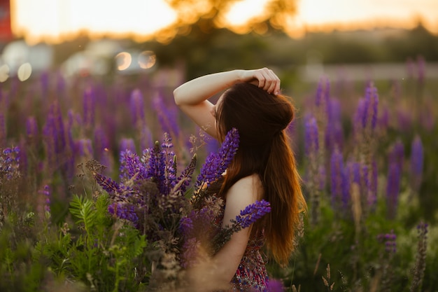 Fiori della holding della ragazza. Bruna in campo. tramonto