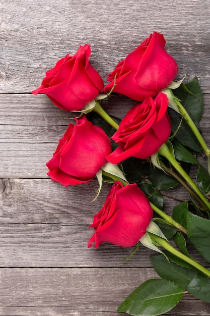 Fiori delle rose rosse sulla tavola di legno grigia. Biglietto di auguri di San Valentino. Vista dall'alto. Copia spazio - Immagine