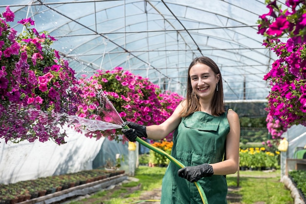 Fiori di bellezza d'innaffiatura della giovane scuola materna femminile nella sua serra