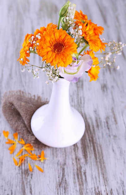 Fiori di calendula in vaso su sfondo di legno