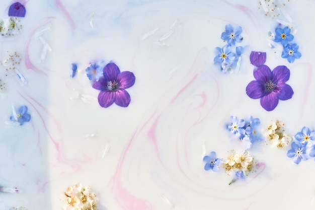 Fiori di campo in acqua lattiginosa con striature di vernice Immagine di sfondo astrazione viola e blu Tenerezza e leggerezza