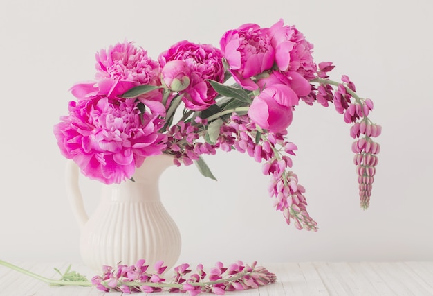 Fiori di peonia in vaso sul muro bianco