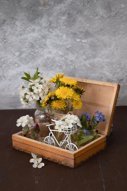 Fiori di primavera in barattoli e una bicicletta in una scatola di legno vintage. Natura morta di primavera.