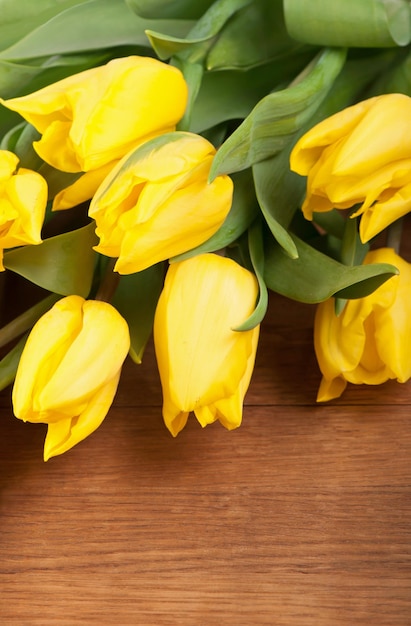 Fiori di primavera luminosi tulipani gialli su sfondo di legno