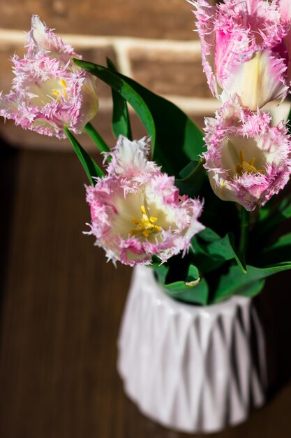 Fiori di primavera Tulipani di spugna in un vaso contro un davanzale marrone e un muro di mattoni