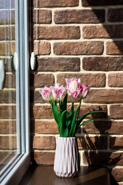 Fiori di primavera Vaso con tulipani vicino alla finestra Muro di mattoni