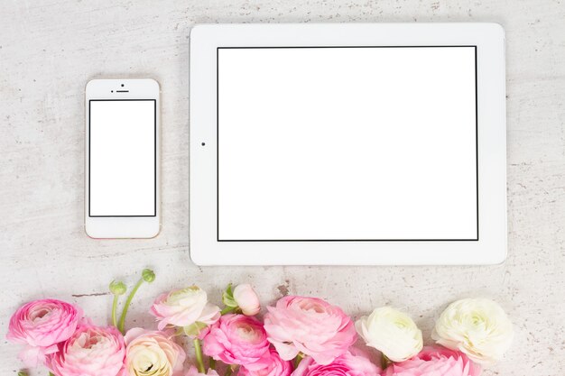 Fiori di ranuncolo rosa e bianchi in stile scena piatta con tablet e cellulare