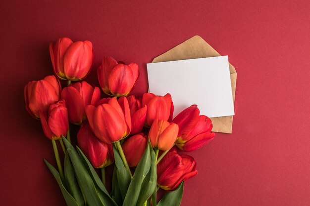 Fiori di tulipano con una carta su sfondo rosso