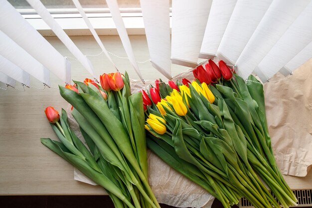 Fiori di tulipano freschi colorati sul davanzale vicino alle persiane