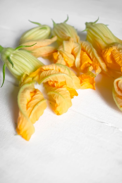 Fiori di zucca su un tavolo di legno bianco Su uno sfondo bianco fiori di zucca arancione Fiori di zucca per il cibo
