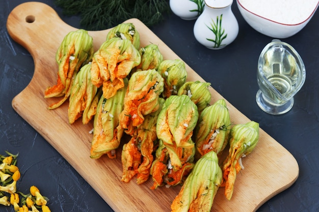 Fiori di zucchine ripieni di formaggio si trovano su una tavola di legno