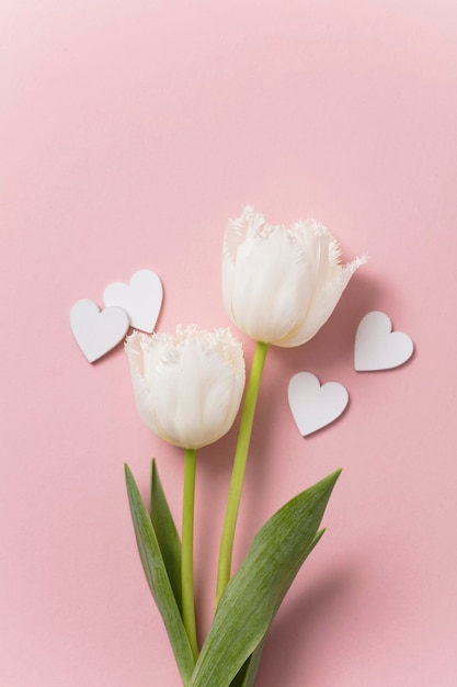 Fiori e cuori bianchi su sfondo rosa pastello